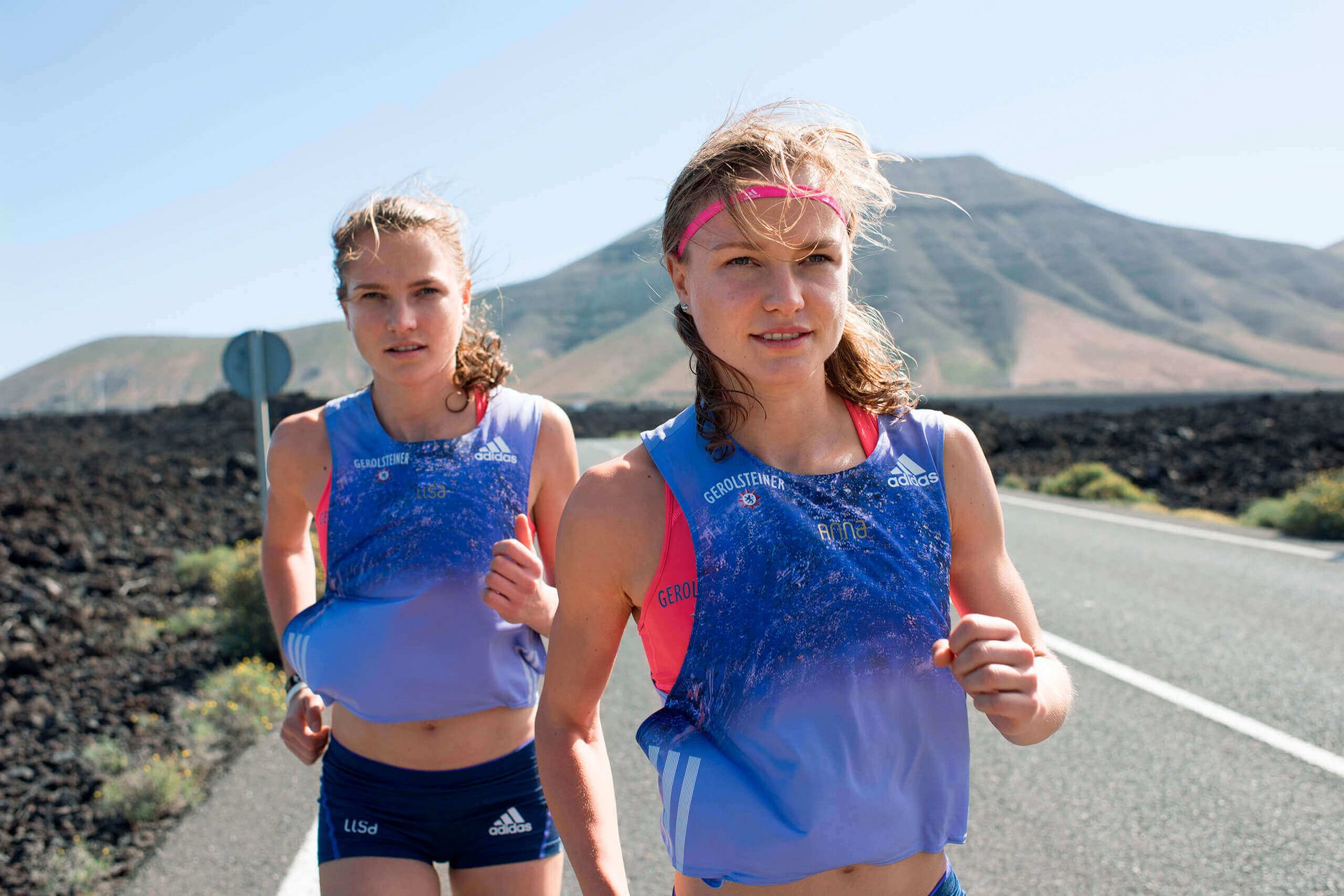 Anna und Lisa Hahner, erfolgreiche Läuferinnen, laufen an einer Straße entlang. Sie sind offizieller Partner von Bauerfeind.
