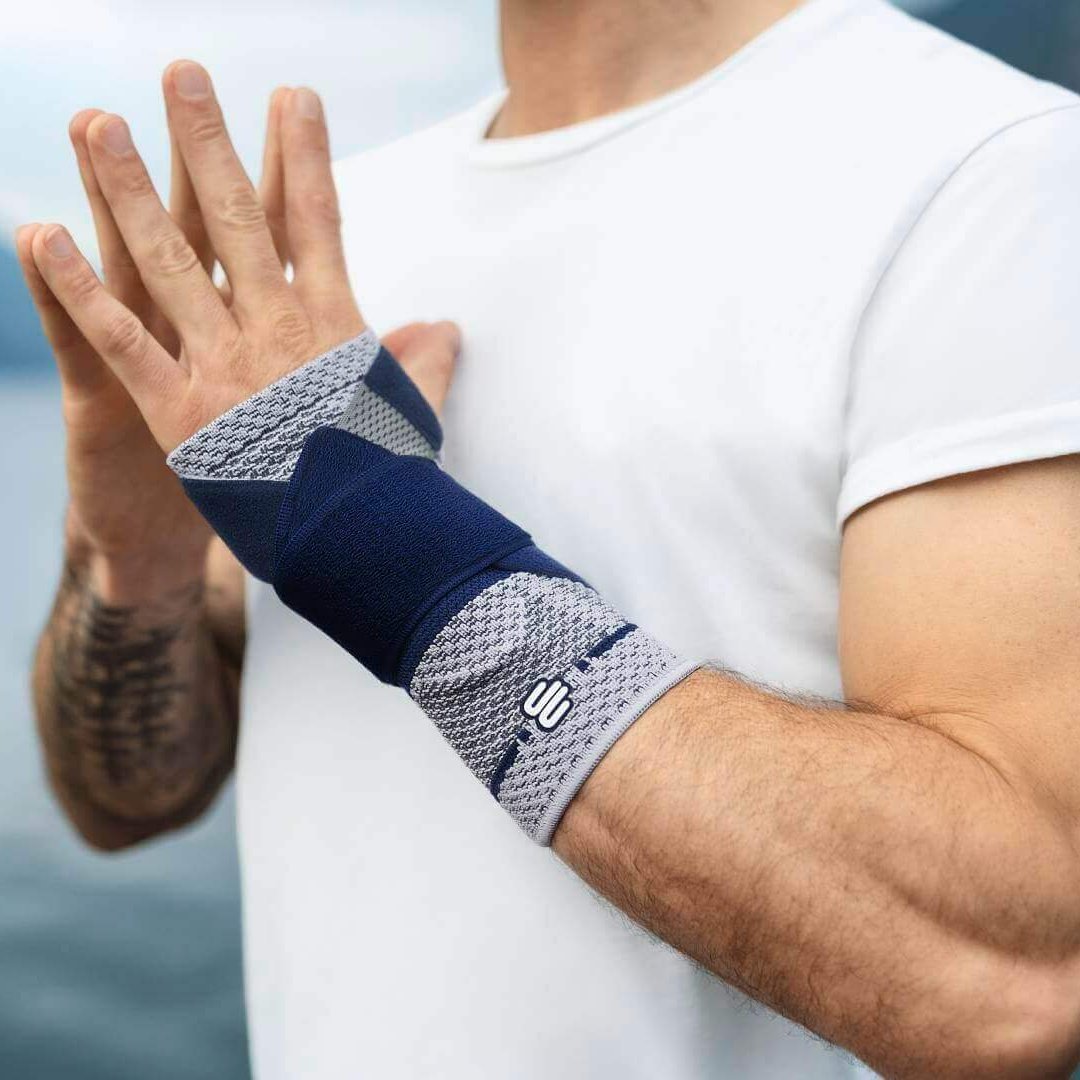 Bildausschnitt eines Mannes an einem See, der eine Yoga-Pose einnimmt und dabei eine ManuTrain Handgelenkbandage trägt, um Schmerzen im Handgelenk zu lindern.