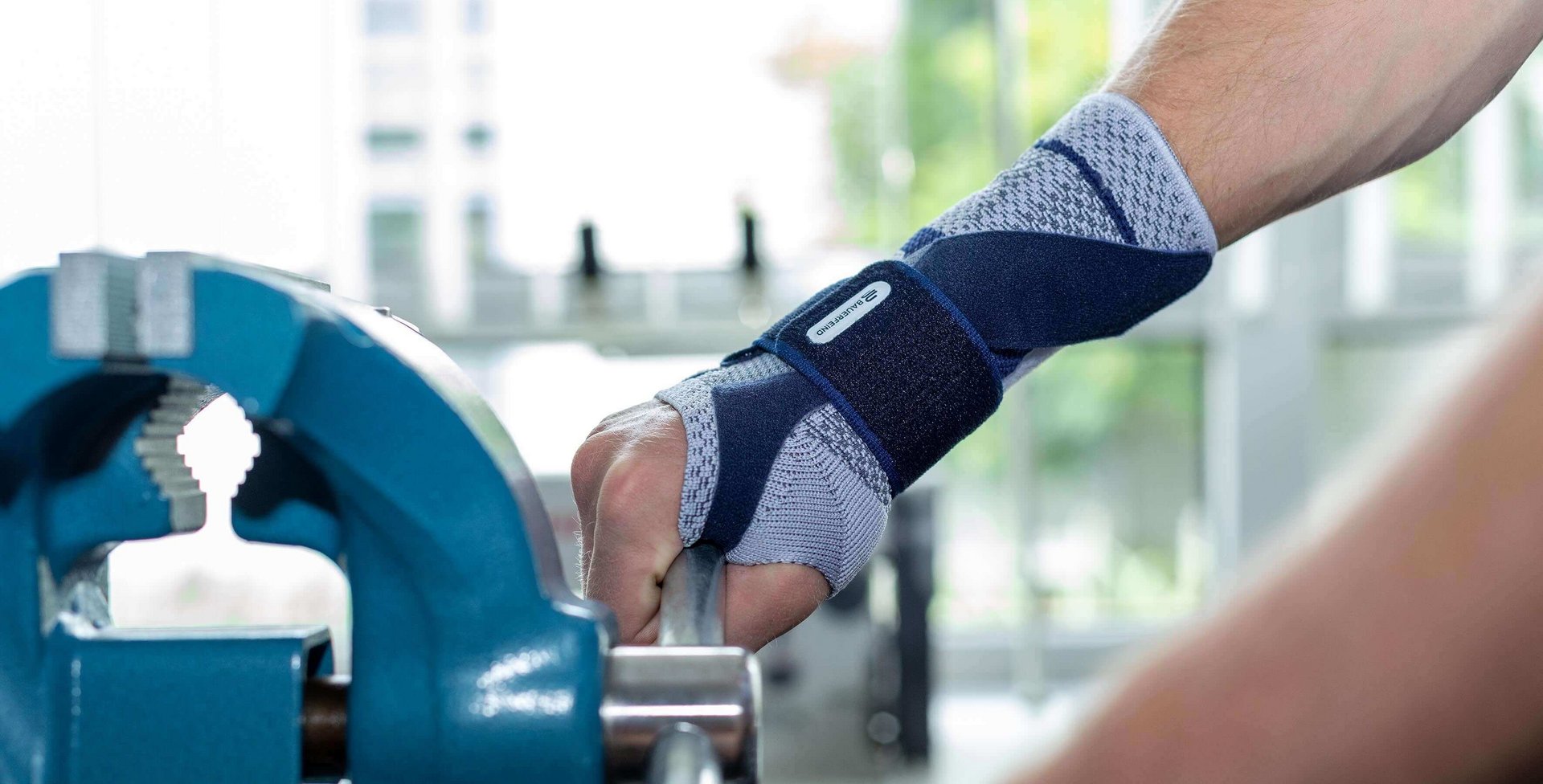 Bildausschnitt eines Mannes beim Arbeiten an einem Schraubstock. An der rechten Hand trägt er eine ManuTrain Bandage von Bauerfeind. Diese bietet u.a. Unterstützung bei einer Sehnenscheidenentzündung.