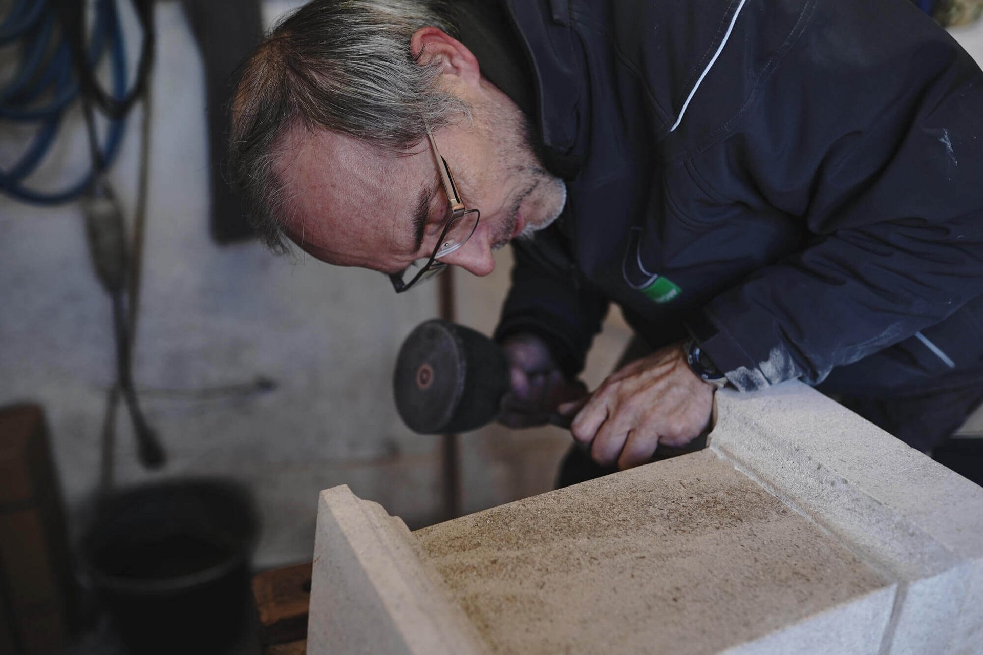 Ein Steinmetz arbeitet in seiner Werkstatt an einem Stein.