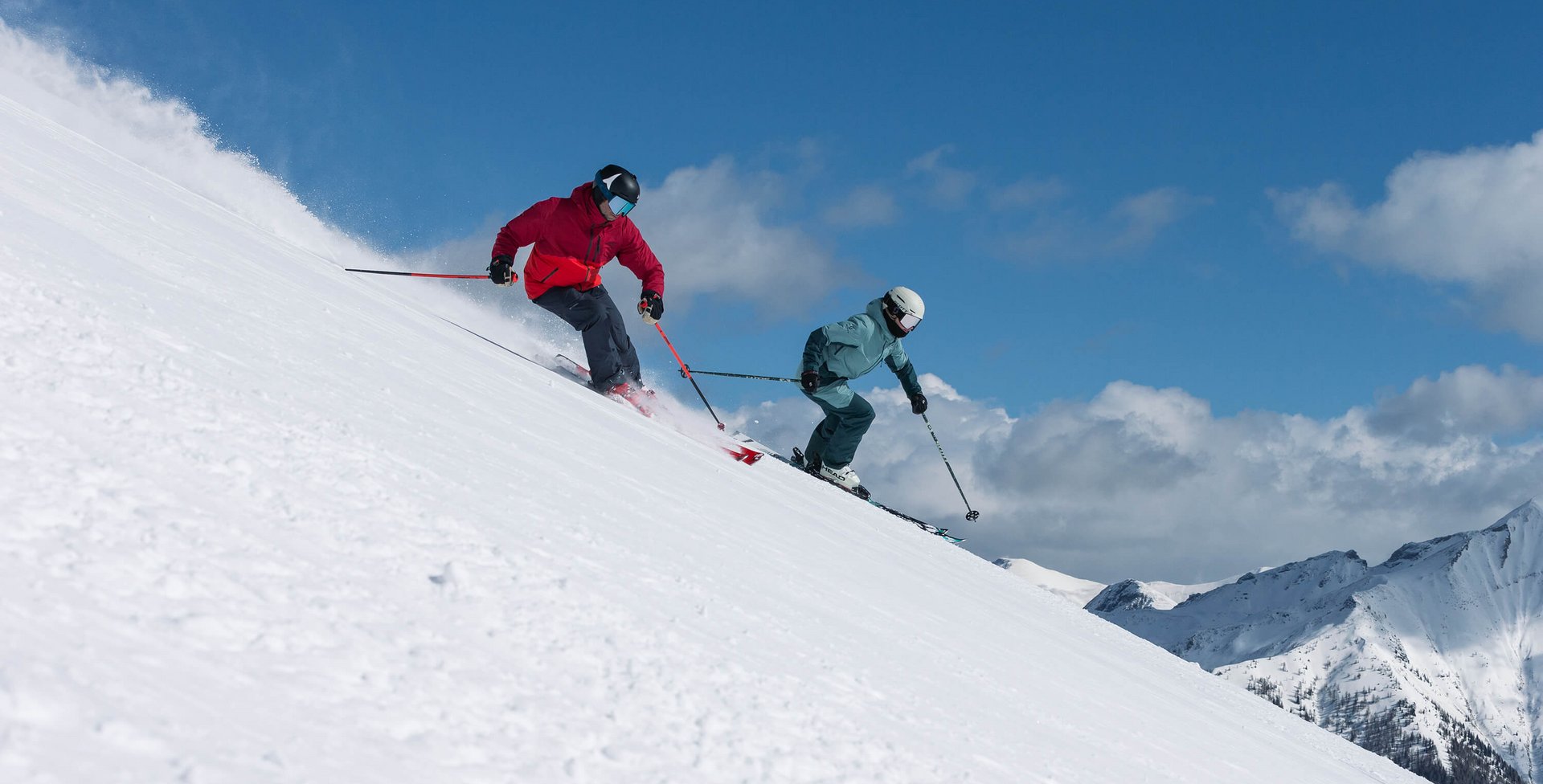Zu sehen sind zwei Skifahrer, die gerade auf einer Abfahrt sind.