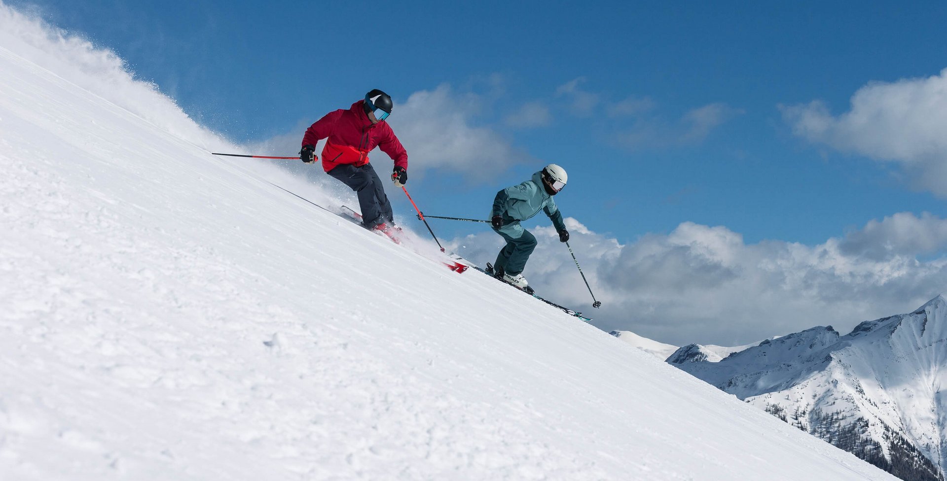 Zu sehen sind zwei Skifahrer, die gerade auf einer Abfahrt sind.