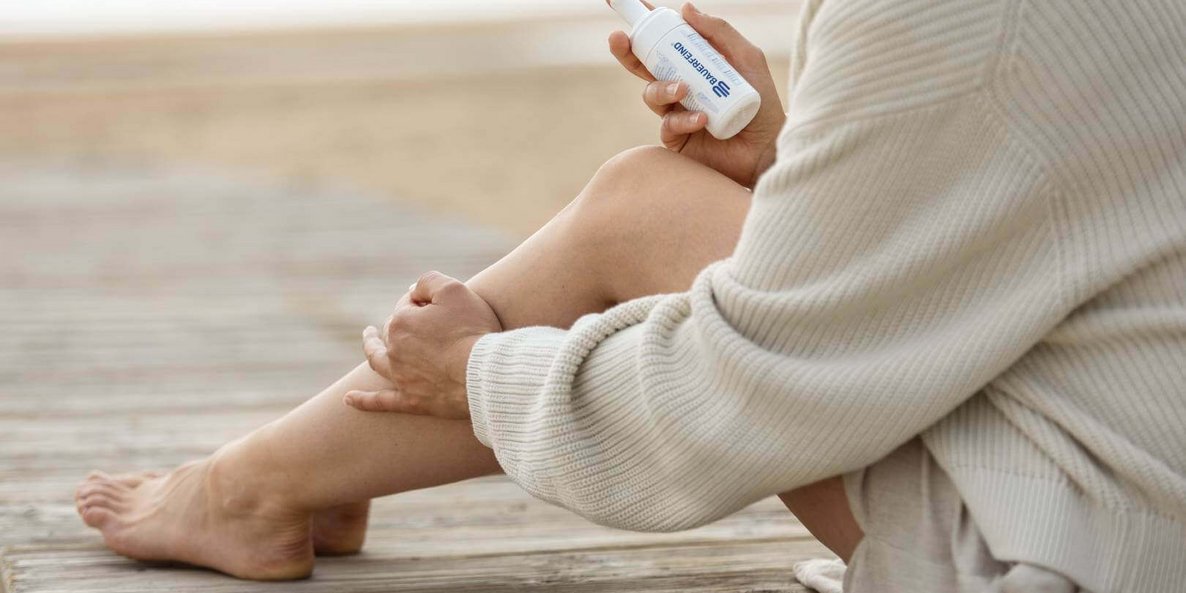 Auf dem Bild ist eine Person zu sehen, die ein Hautpflegeprodukt in der Hand hält. Sie cremt sich gerade mit diesem ein.