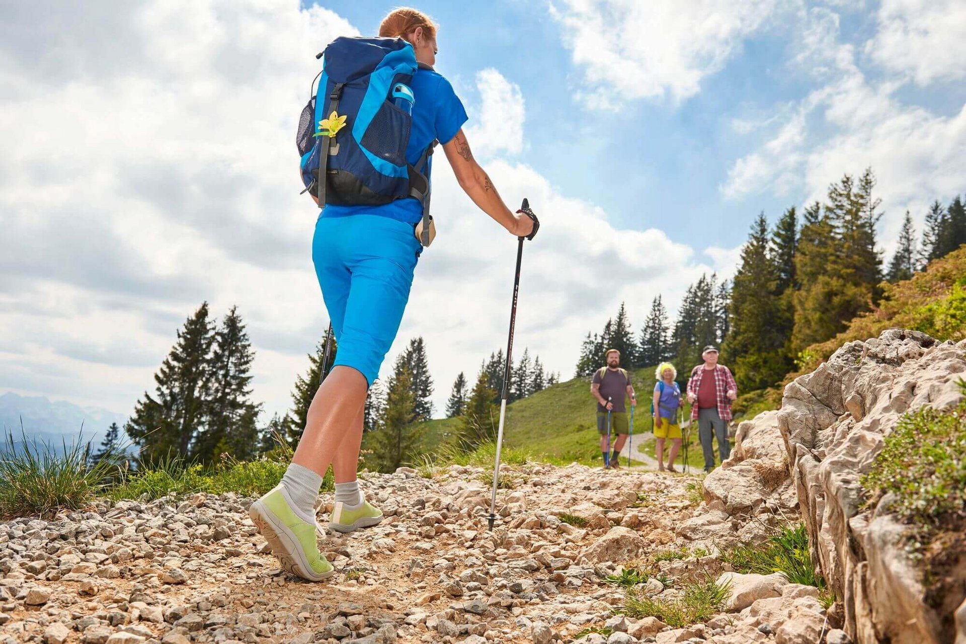 Eine Frau mit Wanderstöcken und Outdoorkleidung läuft einen Wanderweg entlang. Ausreichend körperliche Bewegung ist vorteilhaft, um die Durchblutung sowie die Leistungsfähigkeit des Herzens zu verbessern und somit diabetische Angiopathie vorzubeugen.
