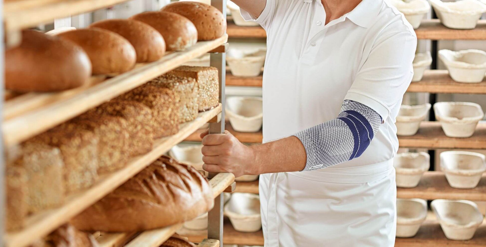 Bildausschnitt eines Bäckers in seiner Backstube. Er trägt eine EpiTrain Ellenbogenmassage von Bauerfeind am linken Arm. Die EpiTrain Bandage lindert Schmerzen im Ellenbogen und verbessert seine Beweglichkeit.