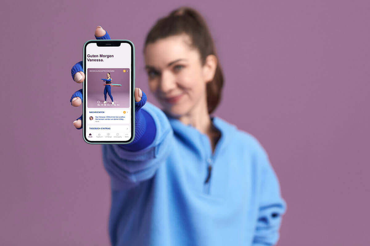 Abgebildet ist eine Frau, die ihr Smartphone mit der Bauerfeind curaflow-App präsentiert. Die App unterstützt Lip- und Lymphödem-Betroffene bei ihrer Therapie.